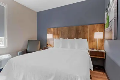 a bedroom with a large white bed and a chair at Extended Stay America Suites - Fort Lauderdale - Plantation in Plantation