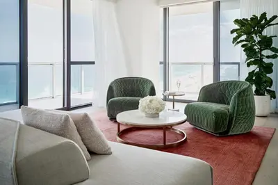 a living room with two green chairs and a table at W South Beach in Miami Beach