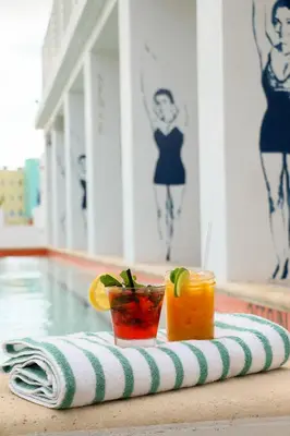 a tray with two drinks on a towel next to a pool at The Local House in Miami Beach