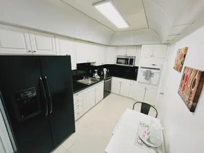a kitchen with white cabinets and a black refrigerator at Hallandale Condo, Partial Ocean View Direct Beach and Pool Access Hollywood Beach in Hollywood