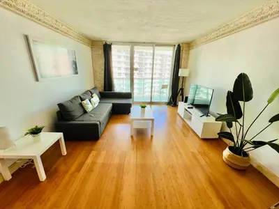 a living room with a black couch and a tv at Hallandale Beach Partial Ocean View Apartments in Hollywood