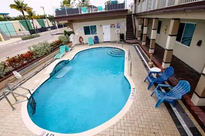 a large swimming pool with two blue chairs and a building at Caribbean Resort Suites in Hollywood