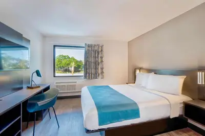 a hotel room with a bed and a desk and a window at Motel 6-Fort Lauderdale, FL in Fort Lauderdale