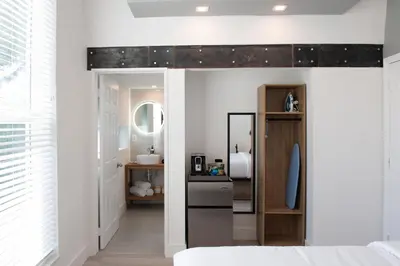 a bedroom with white walls and a wall with a mirror at The Lauderdale Boutique Hotel in Fort Lauderdale