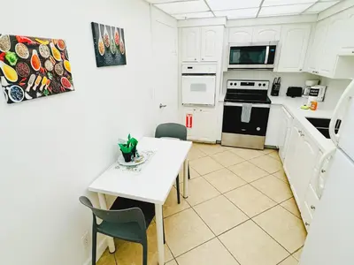 a kitchen with white cabinets and a white table and chairs at Miami Hollywood 2 Bedroom Garden View 001-21mar in Hollywood