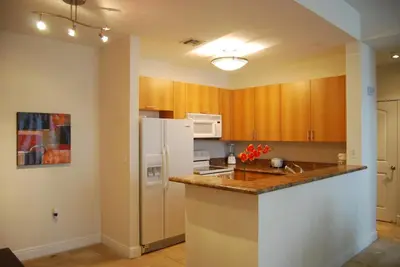 a kitchen with wooden cabinets and a white refrigerator at Dadeland Towers by Miami Vacations in South Miami