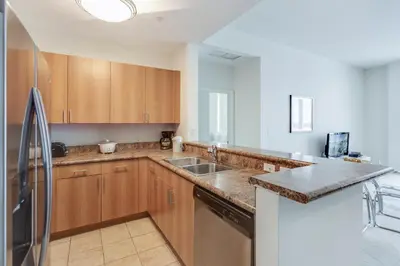 a kitchen with wooden cabinets and a stainless steel refrigerator at Dadeland Towers by Miami Vacations in South Miami