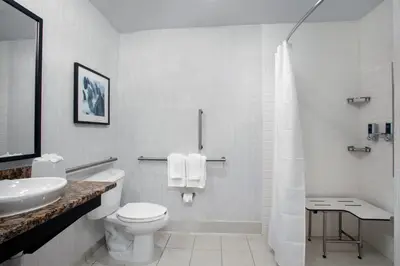 a white bathroom with a toilet and a sink at Four Points by Sheraton Fort Lauderdale Airport - Dania Beach in Dania Beach