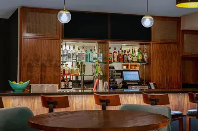 a restaurant with a bar with a table and chairs at Four Points by Sheraton Fort Lauderdale Airport - Dania Beach in Dania Beach