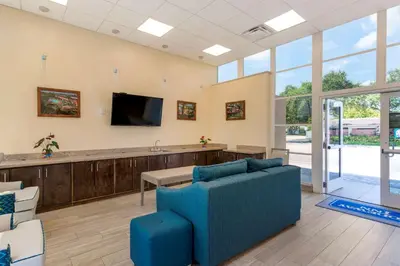 a waiting room with a couch and a flat screen tv at Downtown Hollywood Gardens Inn & Suites in Hollywood