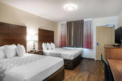 a hotel room with two beds and a flat screen tv at Downtown Hollywood Gardens Inn & Suites in Hollywood