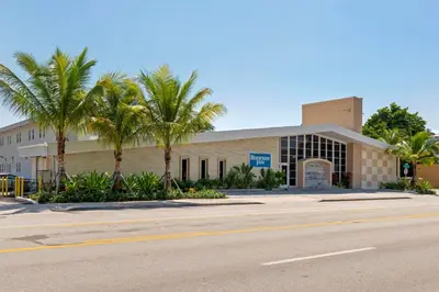 a building with palm trees in front of a street at Downtown Hollywood Gardens Inn & Suites in Hollywood