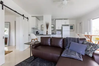 a living room with a brown couch and a kitchen at Spectacular view on the canal, Fort Lauderdale, very clean, free Parking & Wifi in Fort Lauderdale
