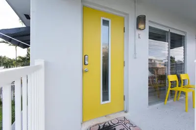 a yellow door on a porch with two chairs at Spectacular view on the canal, Fort Lauderdale, very clean, free Parking & Wifi in Fort Lauderdale