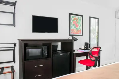 a living room with a tv and a red chair at Quality Inn Miami South in Kendall