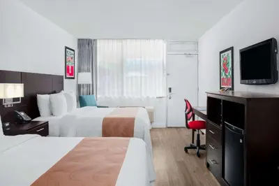 a hotel room with two beds and a television at Quality Inn Miami South in Kendall