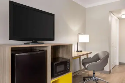 a room with a television and a chair and a desk at Days Inn by Wyndham Miami Airport North in Miami