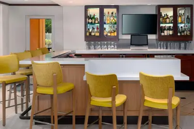 a bar with yellow chairs and a television at Hilton Garden Inn Ft. Lauderdale SW/Miramar in Miramar