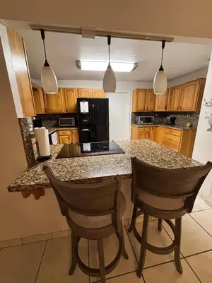a kitchen with a granite counter top and two chairs at 82-10SW 135AV in Miami