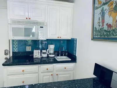 a kitchen with white cabinets and a black counter top at Beachfront Ocean Dr white sand paradise SoBe 311 in Miami Beach