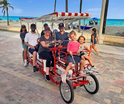 a group of people riding on a redicycle pulled cart at the beach at The Palms in Hollywood