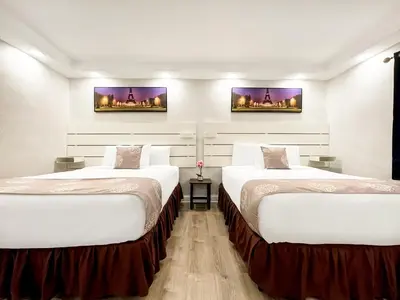 two beds in a hotel room with white walls at The Palms in Hollywood