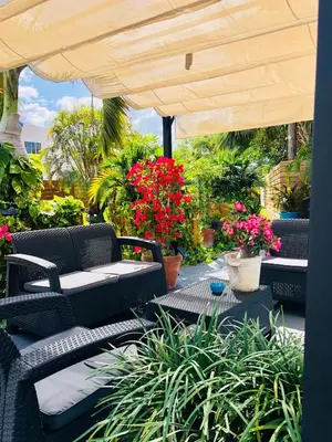 a patio with a table and chairs and flowers at Oasis Hotel in Fort Lauderdale