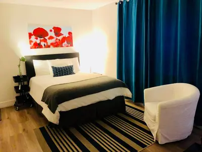 a bedroom with a bed with blue curtains and a chair at Oasis Hotel in Fort Lauderdale