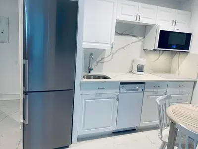 a kitchen with a stainless steel refrigerator and white cabinets at Beach house -magic SoBe 209 in Miami Beach