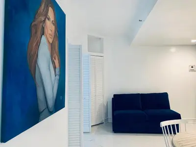 a living room with a blue couch and a painting at Beach house -magic SoBe 209 in Miami Beach