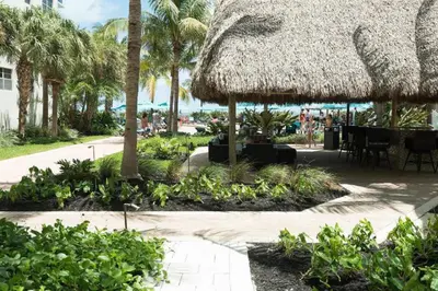 a patio with a straw umbrella and tables and palm trees at Miami Hollywood Two Bedroom Penthouse With Intracoastal View 005-22bvic in Hollywood