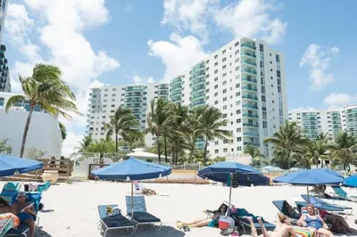 a group of people sitting on a beach with blue umbrellas at Miami Hollywood 2 Bedroom on the Beach 007-21mar in Hollywood
