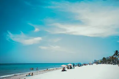 a beach with people sitting on the sand and the ocean at Ocean Drive Villas in Hollywood