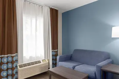 a living room with a blue chair and a window at Super 8 Motel by Wyndham near Fort Lauderdale Arpt in Dania Beach