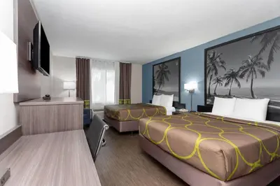 a hotel room with two beds and a television at Super 8 Motel by Wyndham near Fort Lauderdale Arpt in Dania Beach