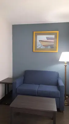 a blue couch in a living room with a table at Super 8 Motel by Wyndham near Fort Lauderdale Arpt in Dania Beach