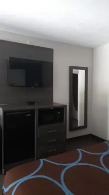 a living room with a flat screen tv and a mirror at Super 8 Motel by Wyndham near Fort Lauderdale Arpt in Dania Beach