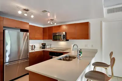a kitchen with wooden cabinets and a stainless steel refrigerator at Miami Midtown Luxury Apartment in Miami