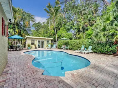a swimming pool with chairs and a house at Vidal Manor in Fort Lauderdale