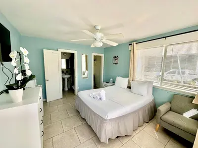 a bedroom with a bed and a couch and a ceiling fan at St Maurice Beach Inn in Hollywood