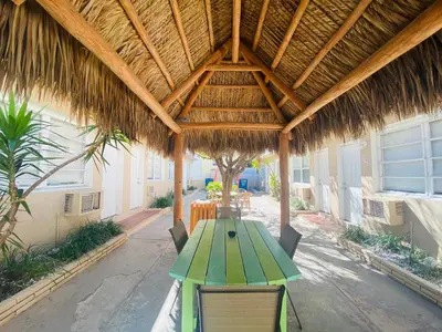 a patio with a table and a straw roof at St Maurice Beach Inn in Hollywood