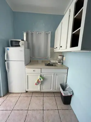 a kitchen with white cabinets and a white refrigerator at St Maurice Beach Inn in Hollywood