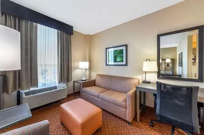 a hotel room with a couch and a desk and a mirror at Best Western Plus Kendall Hotel & Suites in Kendall