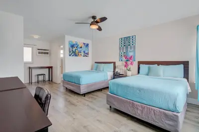 a bedroom with two beds and a table and a dining room at Leeward Motel By Capital O North Miami Beachside in North Miami