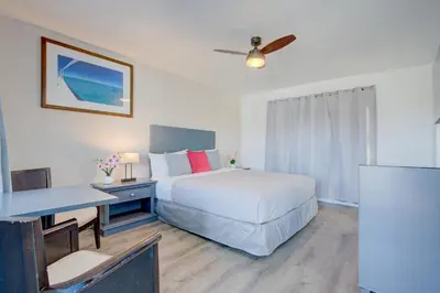 a hotel room with a bed and a desk and a table at Leeward Motel By Capital O North Miami Beachside in North Miami