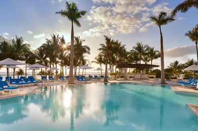 a large pool with blue chairs and palm trees at The St. Regis Bal Harbour Resort in Miami Beach