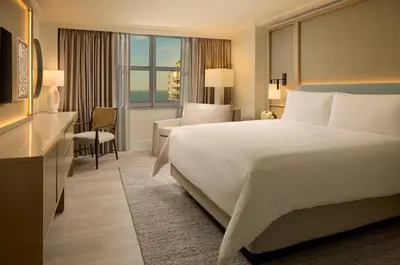 a hotel room with a large bed and a desk at Loews Miami Beach Hotel in Miami Beach