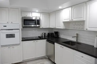 a white kitchen with white cabinets and a microwave at The Tides Miami in Miami
