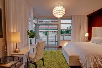 a bedroom with a bed and a desk and a window at Prime Hotel Miami in Miami Beach