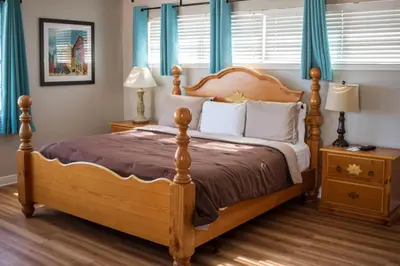 a bedroom with a wooden bed with blue curtains at Riptide Oceanfront Hotel in Hollywood
